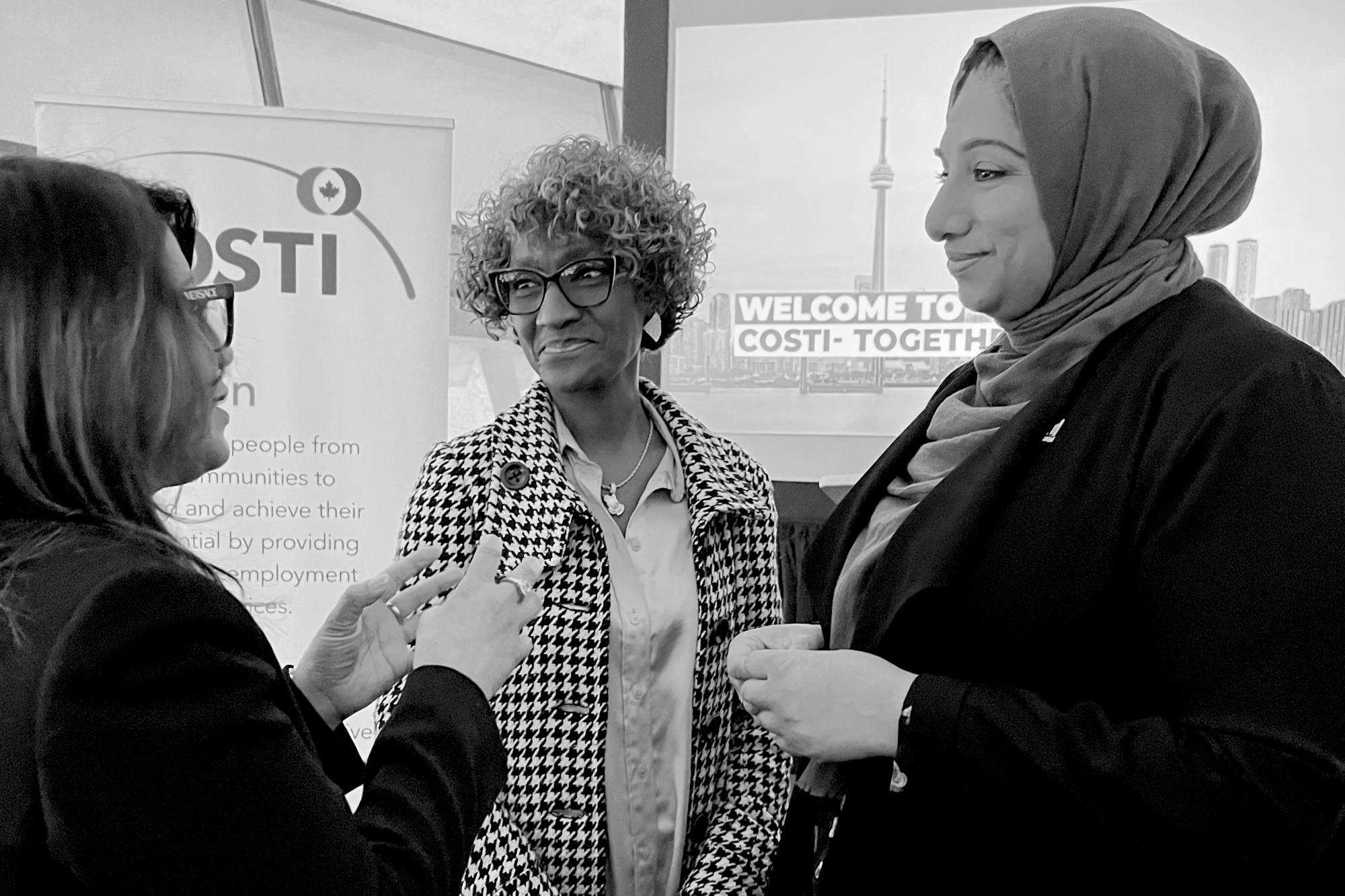 Three diverse women interacting at an event, exchanging thoughts and laughter